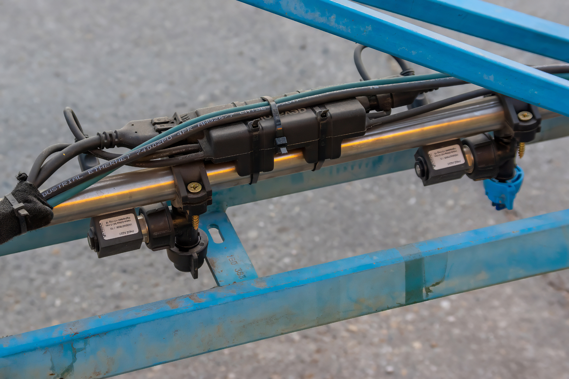 Close-up of the WeedEye TALON high-speed solenoid valve system mounted on a spray boom